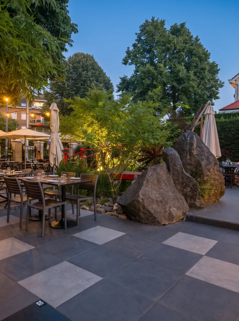 Le jardin japonais à la tombée du jour, les grands rochers éclairés et la terrasse dressée