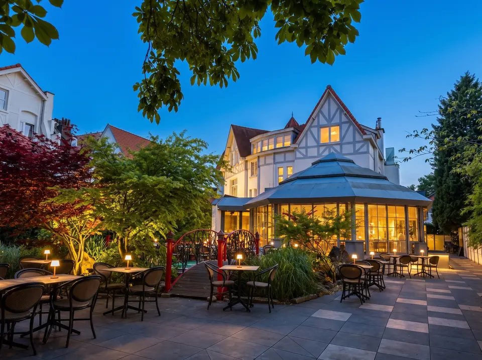 La villa à colombages et sa verrière octogonale éclairées à l'heure bleue, la terrasse et le jardin japonais